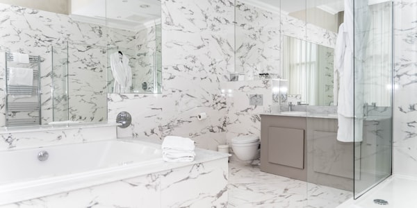 Modern renovated bathroom with marble tile and glass shower